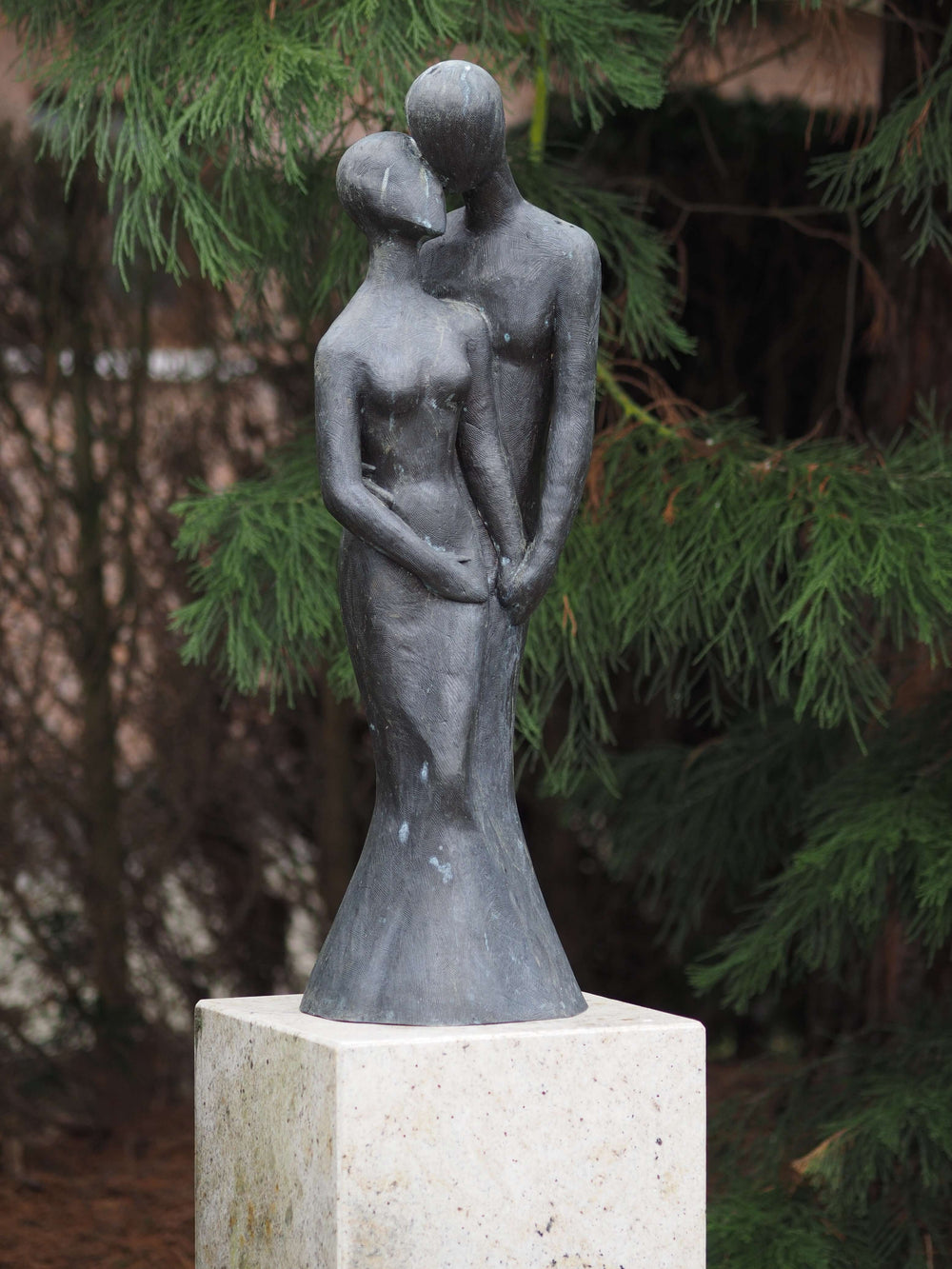 Large bronze sculpture of a loving couple, gracefully designed for outdoor display, on a stone base.