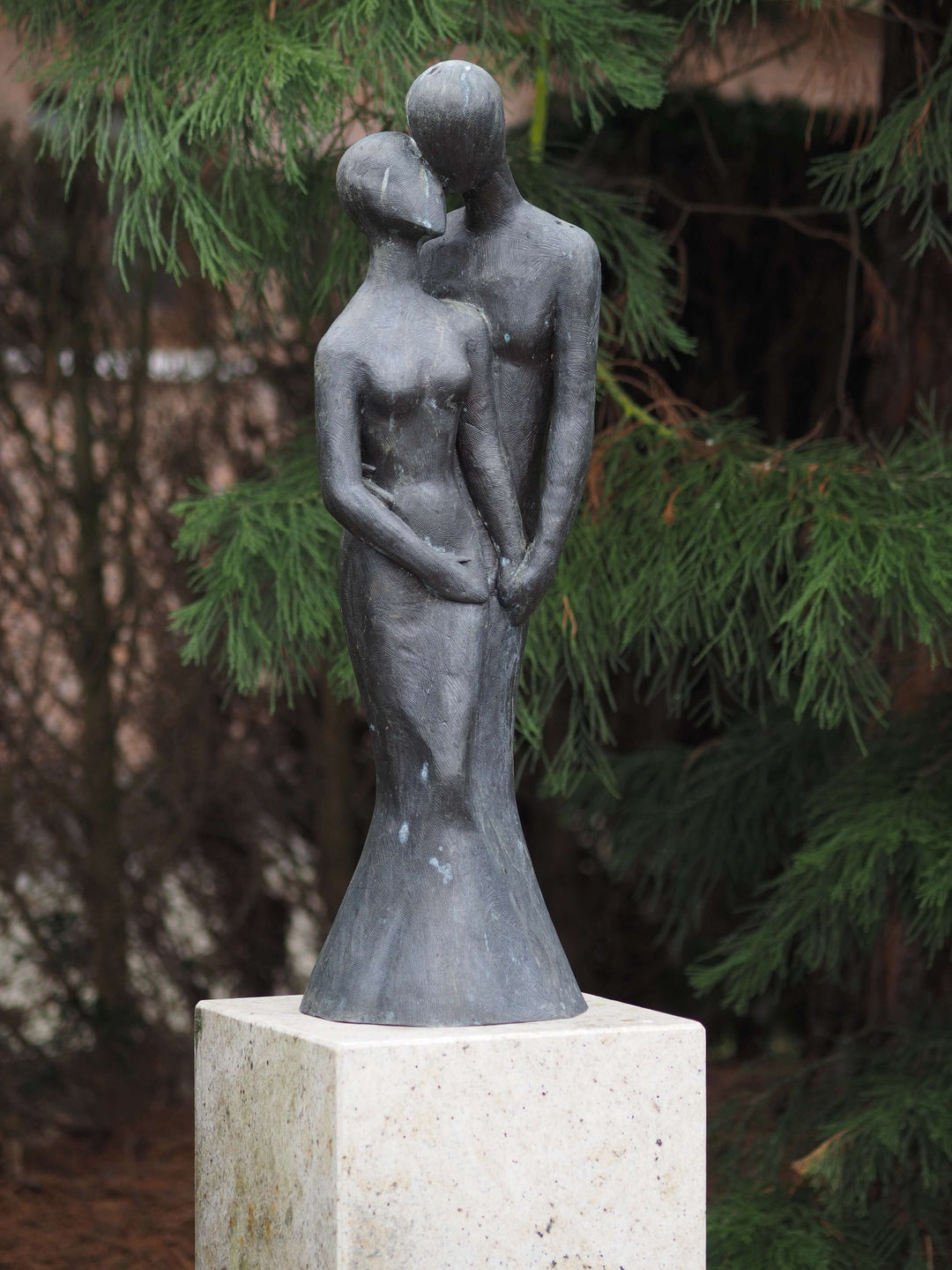 Large bronze sculpture of a loving couple, gracefully designed for outdoor display, on a stone base.