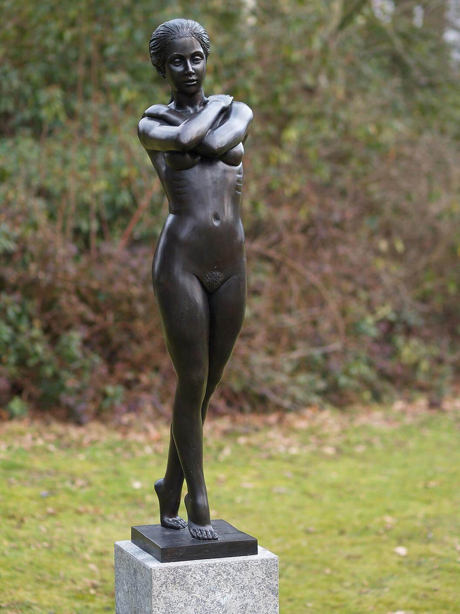 Large bronze sculpture of a standing nude woman with arms crossed, exuding grace and elegance.
