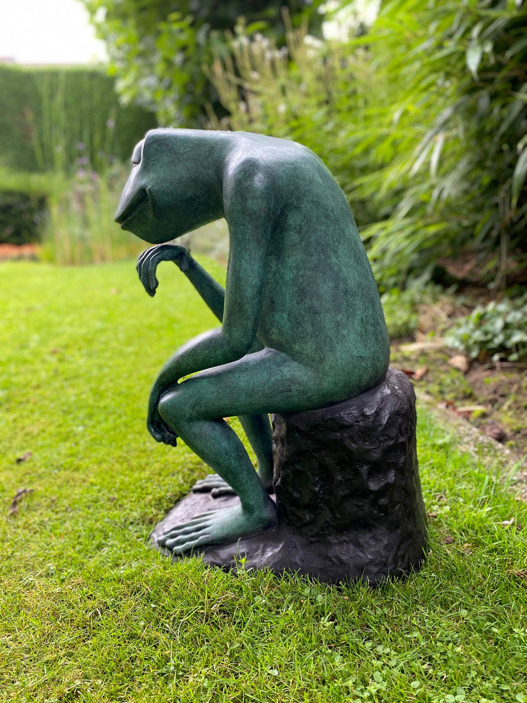 Large bronze sculpture of a pondering frog seated on a rock, showcasing intricate patina and serene expression.