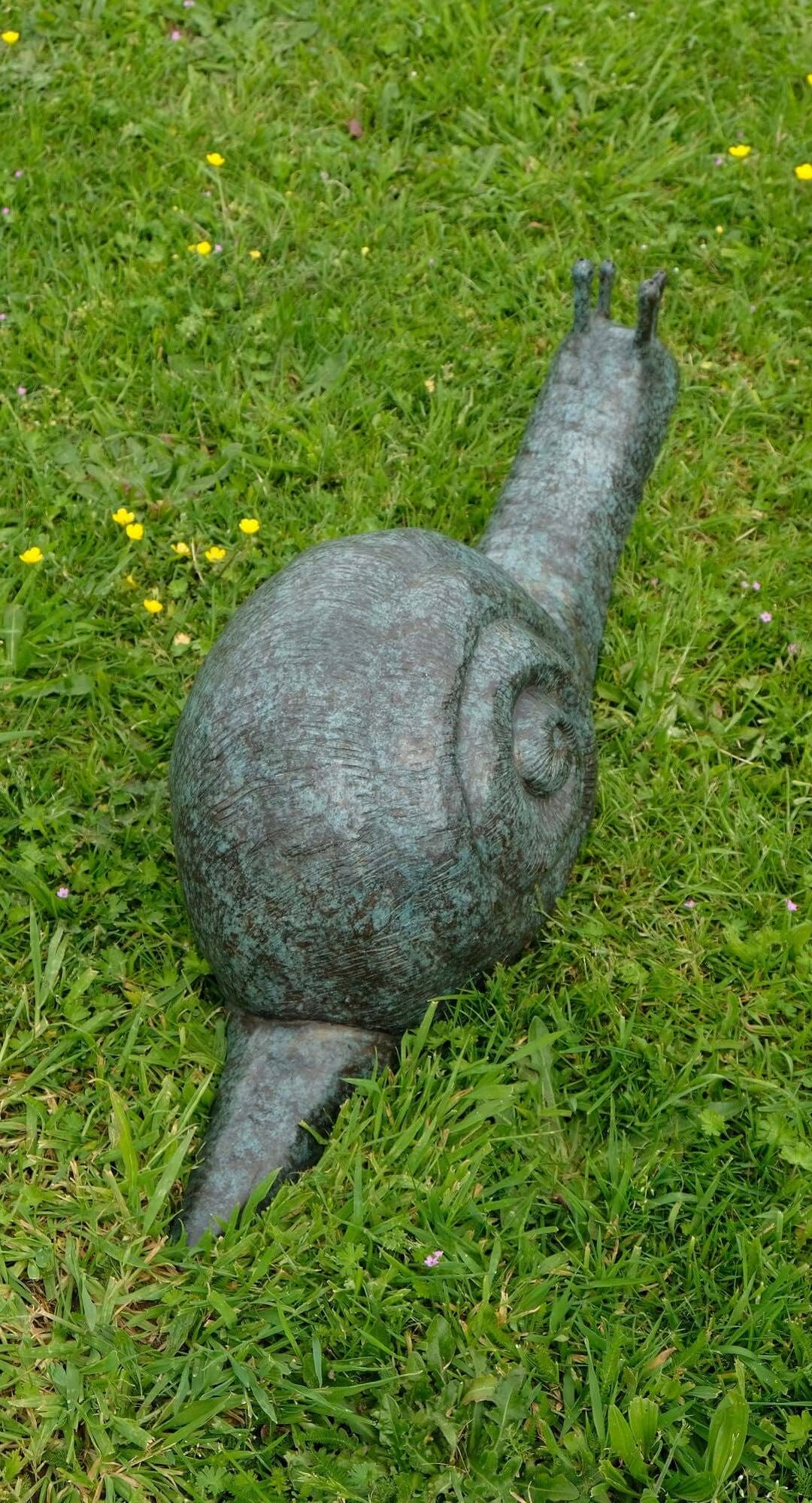 Large bronze snail sculpture resting on green grass, ideal for enhancing outdoor spaces and gardens.