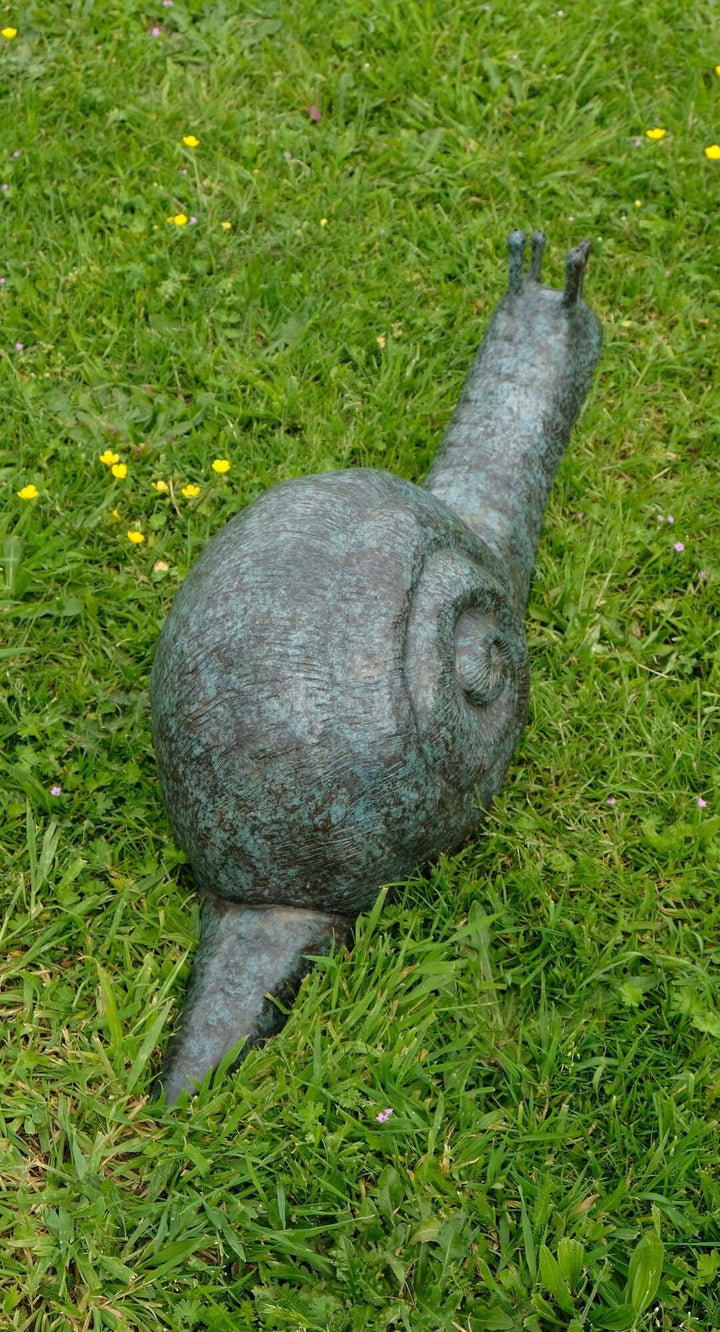 Large bronze snail sculpture resting on green grass, ideal for enhancing outdoor spaces and gardens.