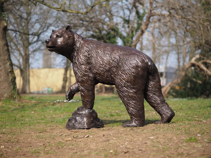 Lifesize bronze bear sculpture with raised paw, detailed wildlife art, perfect for outdoor display in gardens.