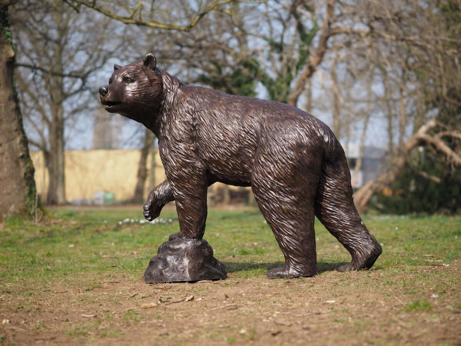 Lifesize bronze bear sculpture with raised paw, detailed wildlife art, perfect for outdoor display in gardens.