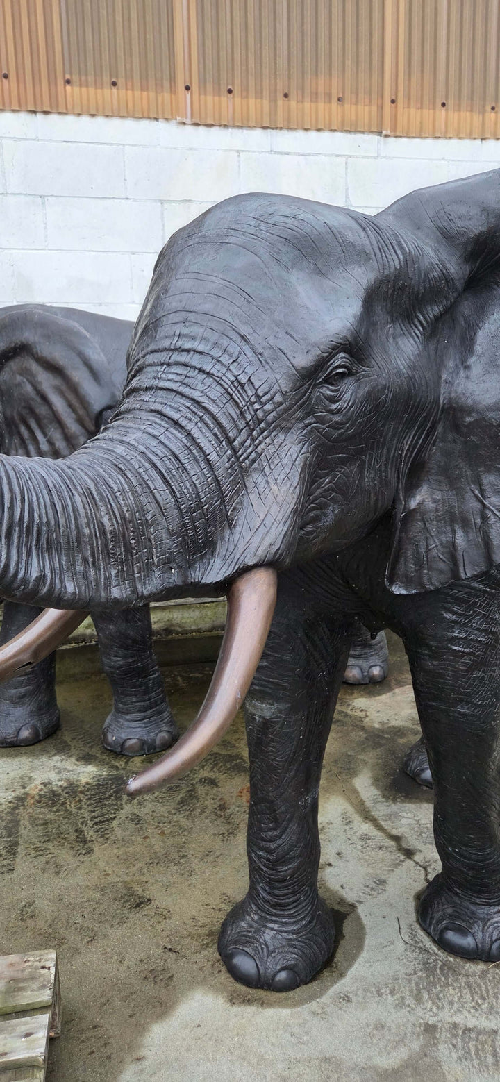 Lifesize bronze elephant sculpture with trunk raised, showcasing detailed features and elegant design.