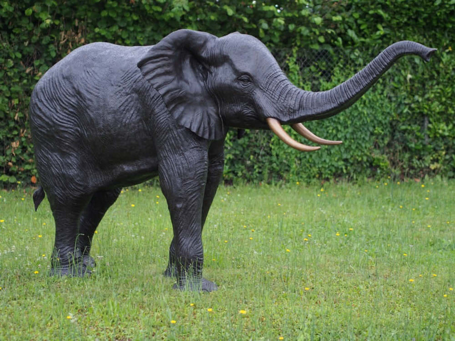 Lifesize bronze elephant sculpture with raised trunk, showcasing exceptional detail and dark patina for outdoor display.