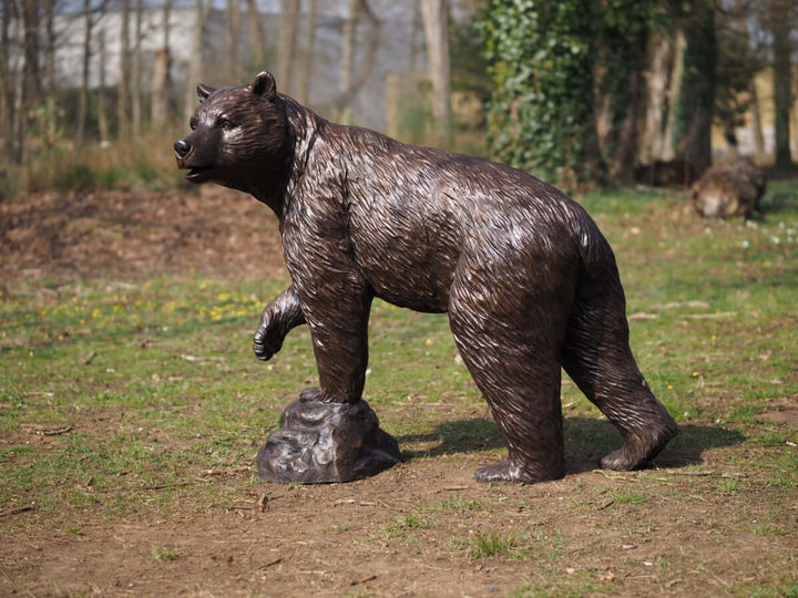 Lifesize bronze bear sculpture with raised paw, detailed wildlife art, perfect for outdoor display.