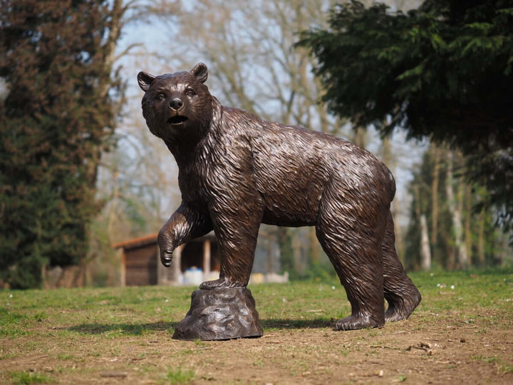 Lifesize bronze bear sculpture with raised paw, detailed artwork for outdoor garden display.