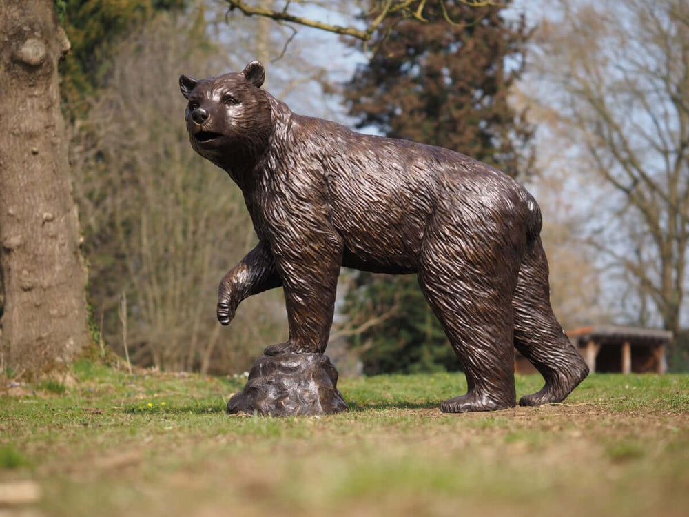 Lifesize bronze sculpture of a bear with raised paw, beautifully detailed wildlife art for outdoor display.