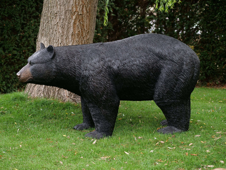 Lifesize bronze black bear sculpture in an outdoor setting, showcasing detailed craftsmanship and natural design.