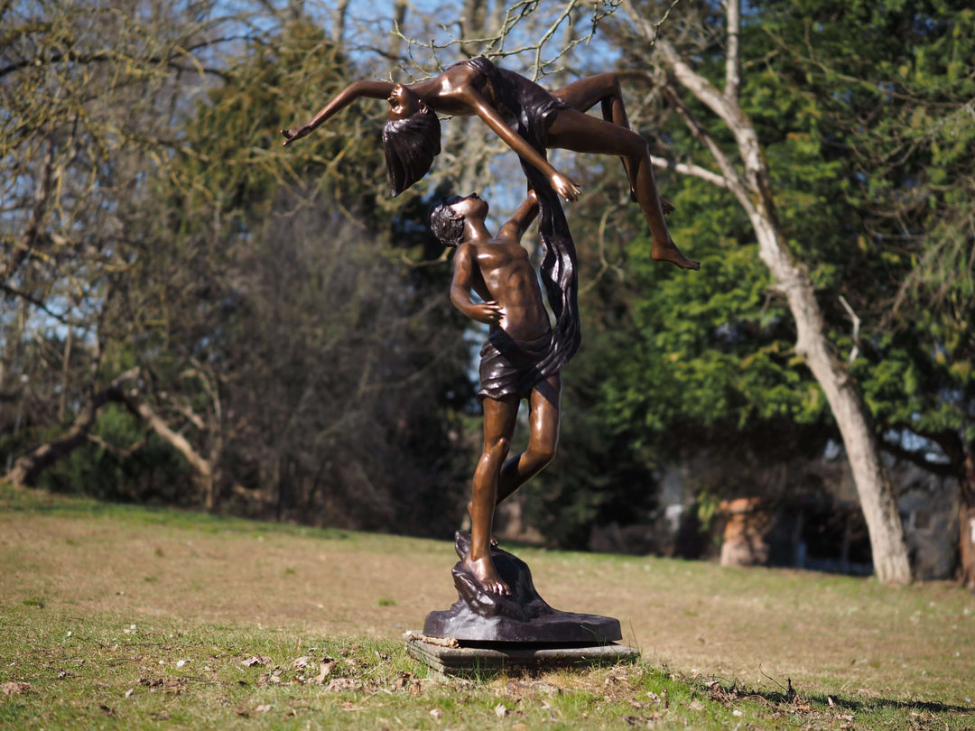 Lifesize bronze sculpture of a couple dancing, showcasing elegance and motion in a scenic outdoor setting.