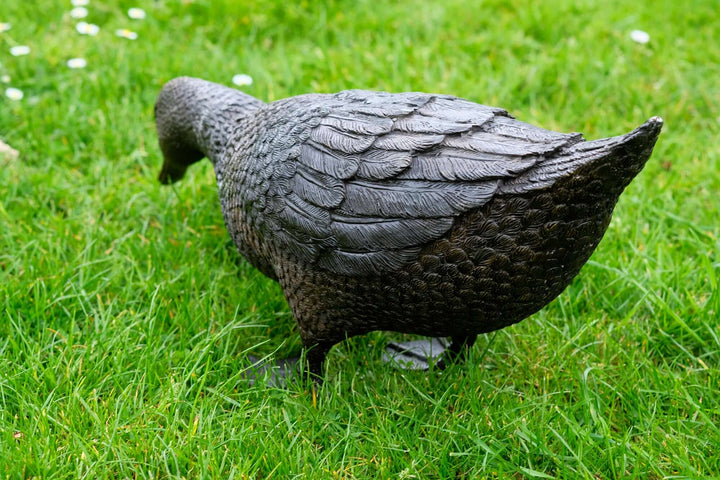 Lifesize bronze sculpture of a foraging duck on grass, showcasing intricate detailing and realistic design.