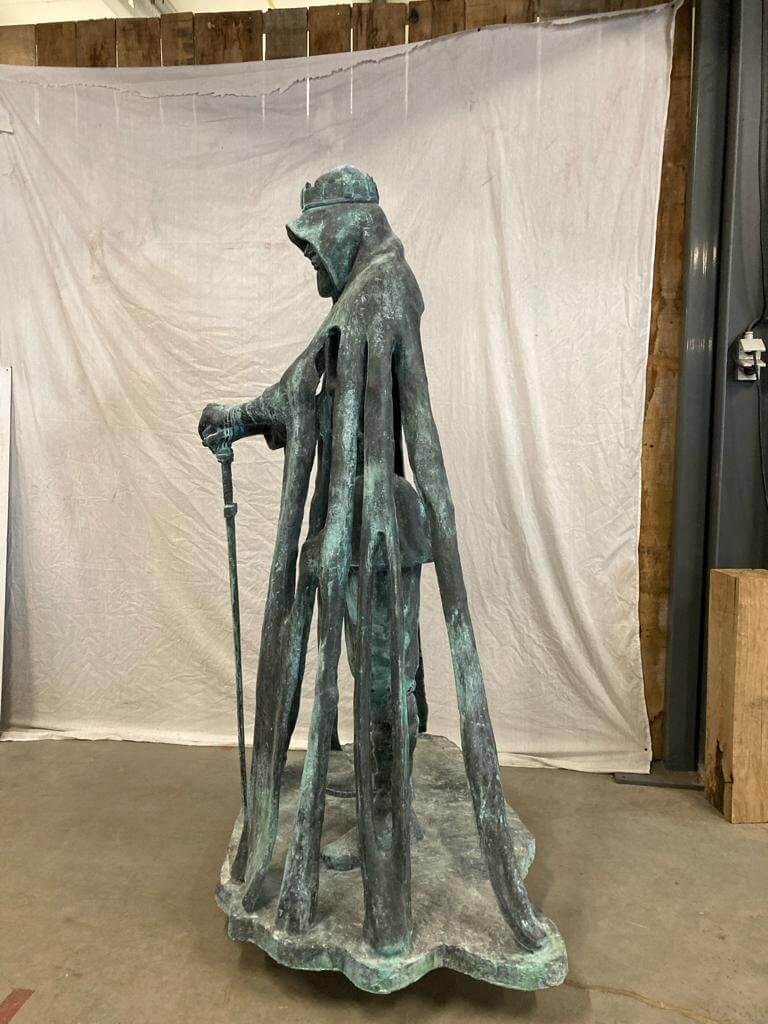 Lifesize bronze sculpture of King Arthur, detailed figure with sword and cape in indoor setting.