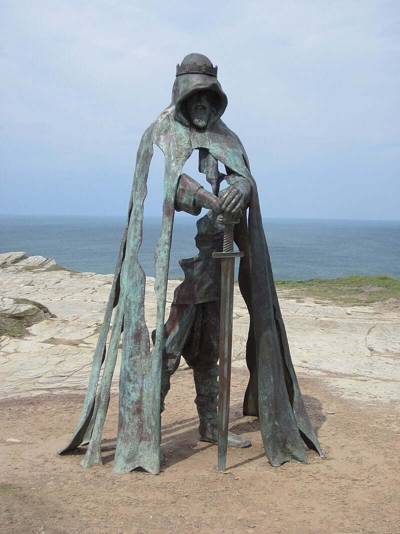 Lifesize bronze sculpture of King Arthur with sword overlooking the sea at Tintagel Castle, Cornwall.