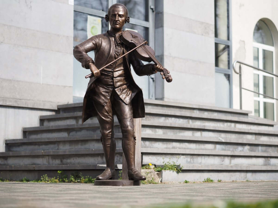 Lifesize bronze sculpture of Mozart playing the violin, elegantly detailed and suitable for outdoor display.