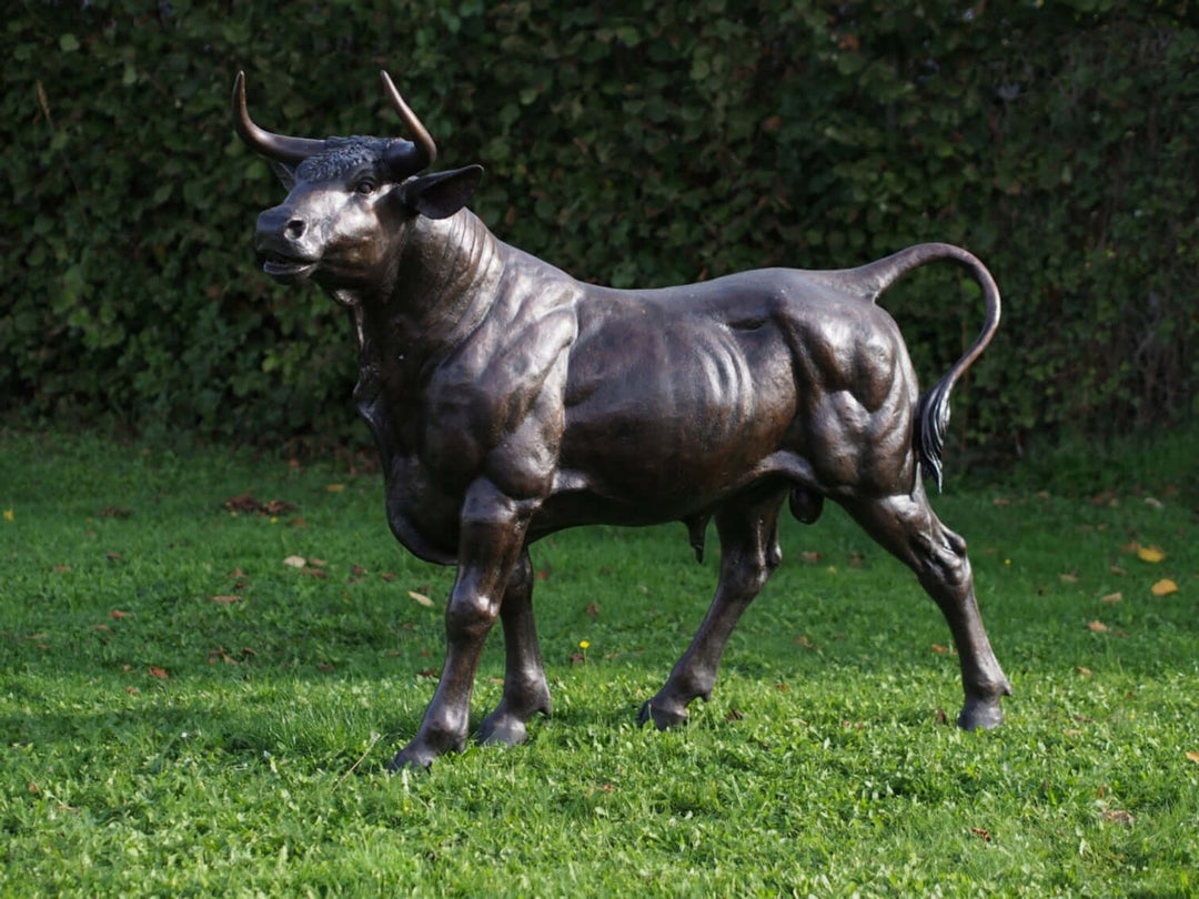 Lifesize bronze sculpture of a standing bull, showcasing realistic detail and powerful stance on grass.