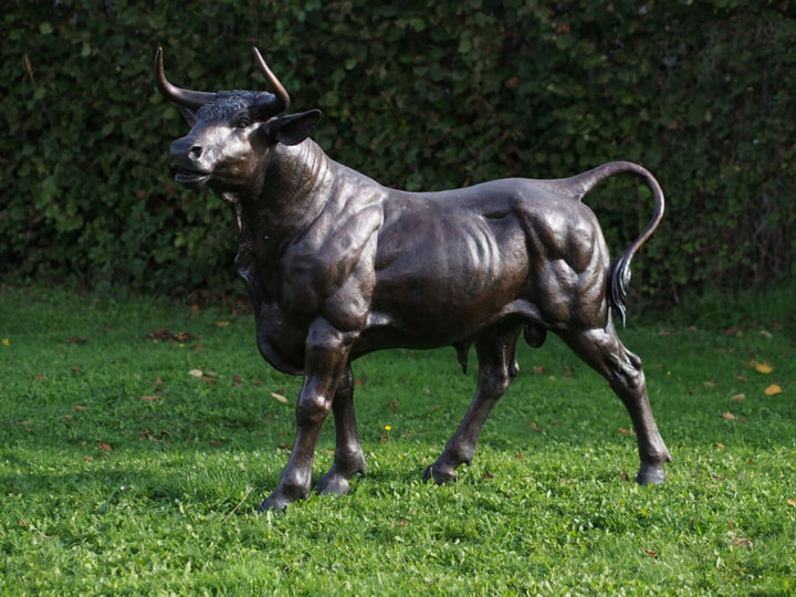 Lifesize bronze sculpture of a standing bull, showcasing realistic detail and powerful stance on grass.