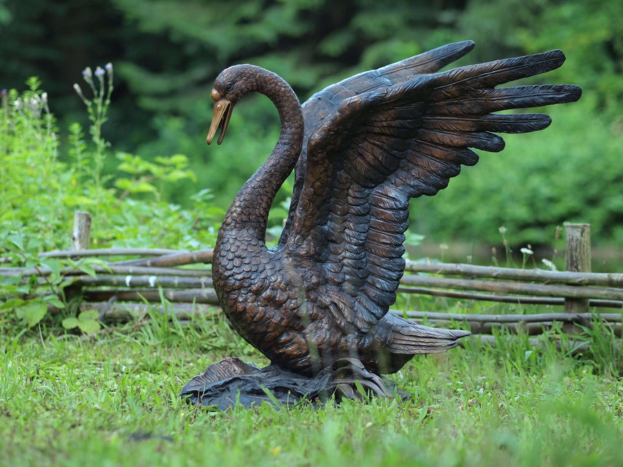 Lifesize bronze swan sculpture with wings spread, detailed design for outdoor elegance and lasting beauty.