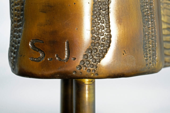Close-up of the artist's signature "S.J." on a luxurious bronze giraffe sculpture mounted on mahogany base.
